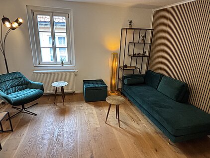 Modernes Sprechzimmer mit türkisfarbenem Sessel und einem Sofa.